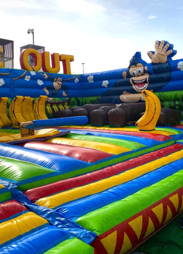 Una selva llena de color Inflable colorido con temática de mono y plátanos, con toboganes y obstáculos.