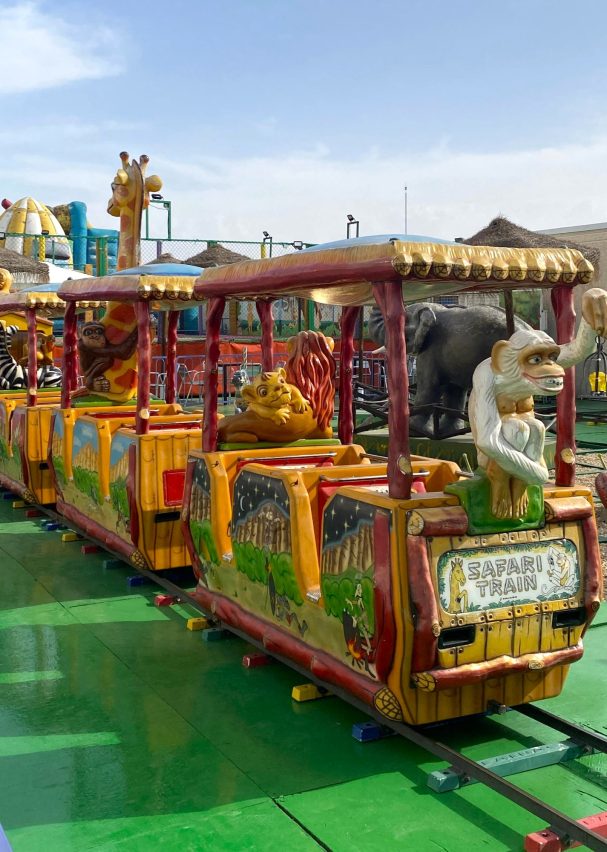El tren por detrás Tren de atracción colorido en un parque de diversiones con decoraciones de animales.