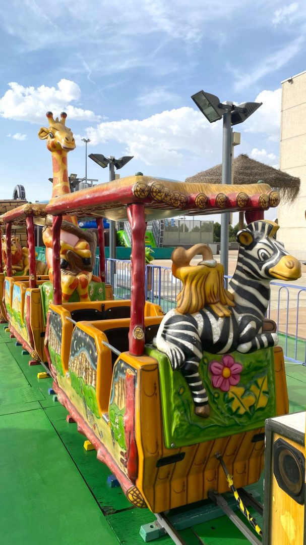 El vagón de la cebra y el avestruz Tren decorado con animales de juguete, como una jirafa y una cebra, en un parque.