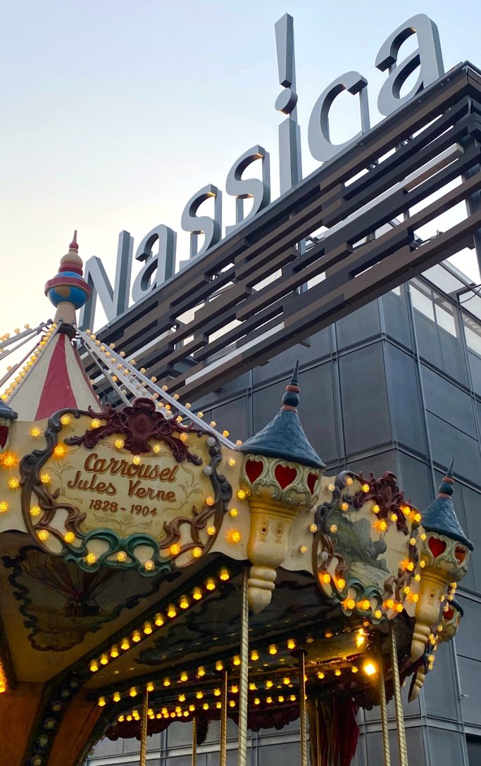 El Carrusel, símbolo de Nassica Caballitos de un carrusel iluminado frente a un edificio moderno con letrero.