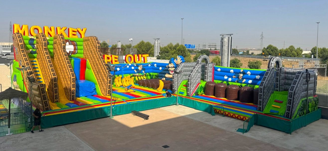 El Monkey Wipeout Zona de juegos inflable colorida con toboganes y obstáculos para niños.