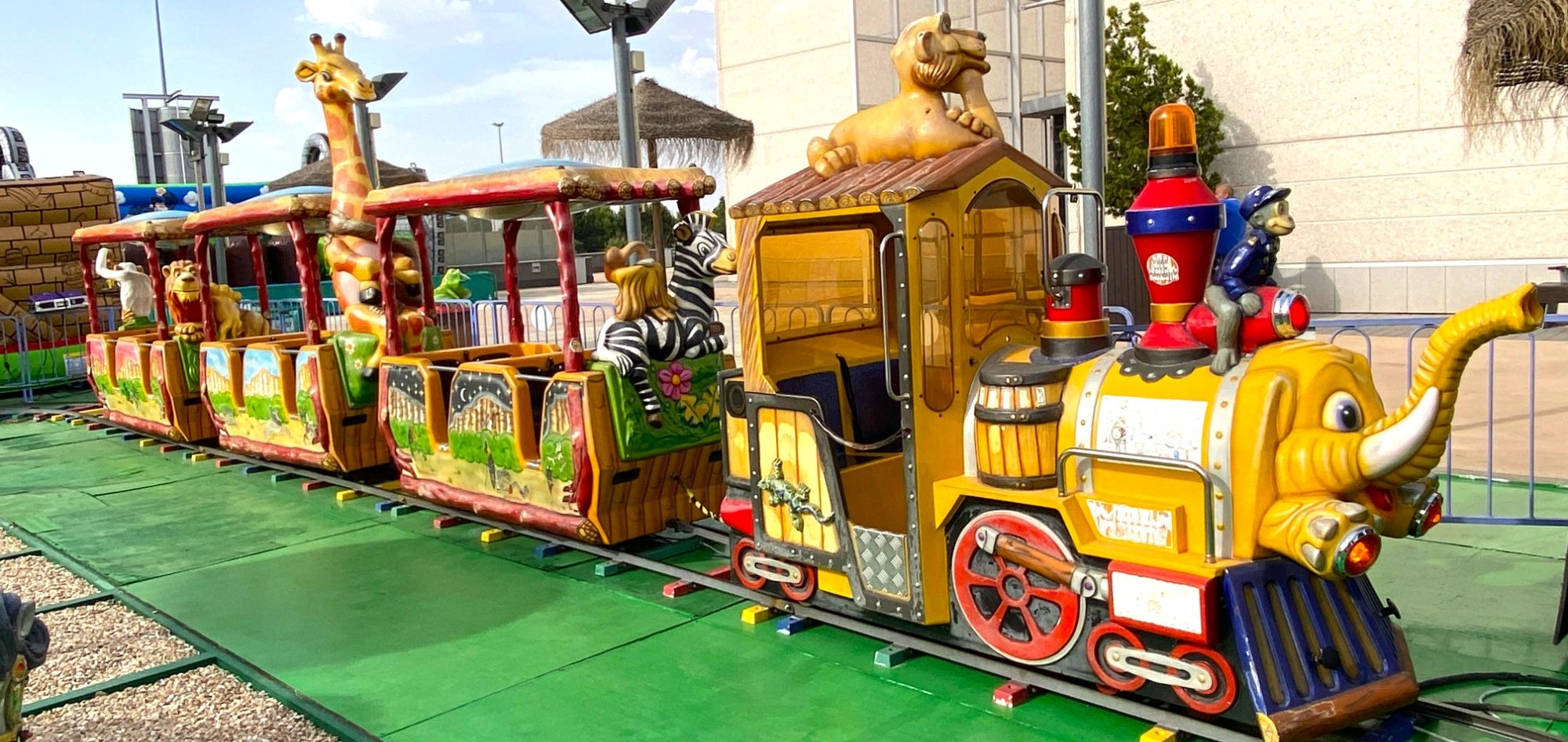 El tren de la selva Tren infantil colorido con animales decorativos en un parque de diversiones.
