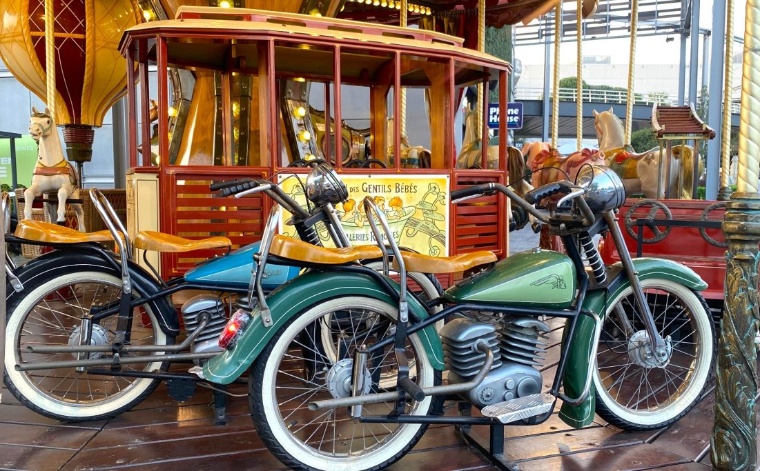 Tren de época y las motos Dos bicicletas clásicas de colores, una azul y otra verde, junto a un carrusel antiguo.